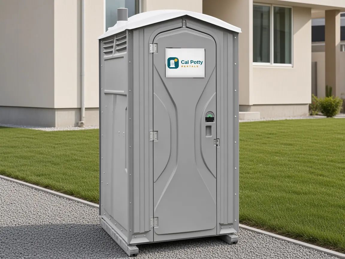 A grey porta potty on a lawn beside a stucco townhome, an example setup for porta potty rental in Los Altos